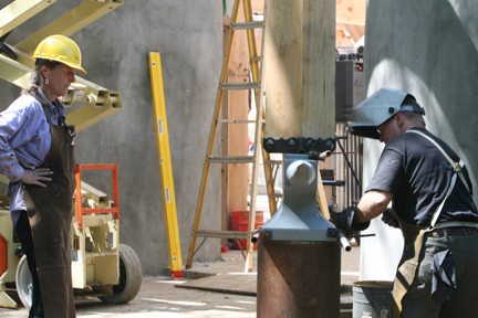 Blacksmiths Julie Clark and Ted Thompson fit an anvil and stump sculpture to a post at the entrance to the new forge building.