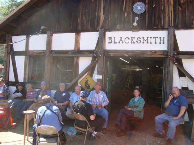 Blacksmith Work Week is a wonderful annual tradition at the Folk School where blacksmiths from all over come and volunteer their time to do smithing projects around campus and make improvements in the Shop. It’s been 15 or 20 years that they have gathered here every spring, for Blacksmith Work Week, so Paul Garrett, the Resident Blacksmith tells me. When I visited, there were about 20 men and at least one woman circling like bees. They are all over the balconies, in corners and down on the floor.  Red hot metal is being pounded beside blazing forges, power hammers have metal running through at a rapid speed, and components are being welded together.  It is high-level intensity with professional focus in the shop today.  No students are here; the blacksmiths are giving their time and talent to retrofit the Francis Whitaker Blacksmith Shop. What was the primary blacksmith shop is now being set up for material storage, welding, grinding, and drilling. A few forges have been left in place for this studio.  ...