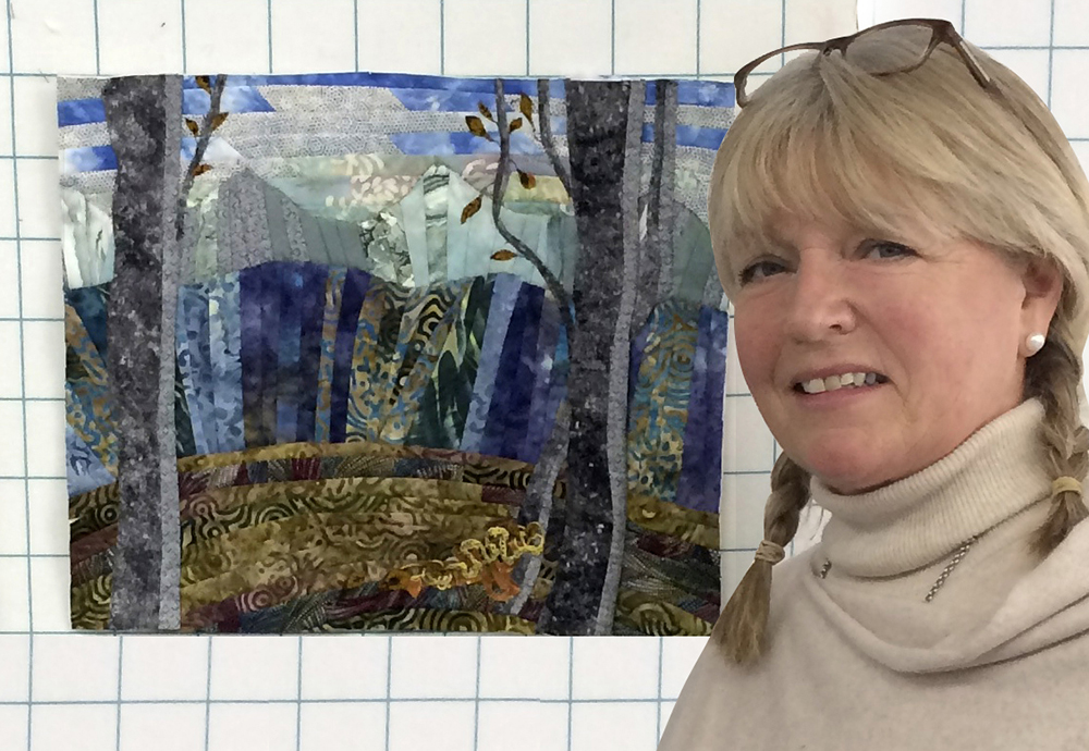 Sissel stands next to her cabin view quilt.