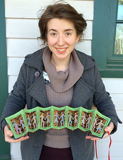 Sara holds the contra dance themed accordion book she made in Annie Cicale's class.