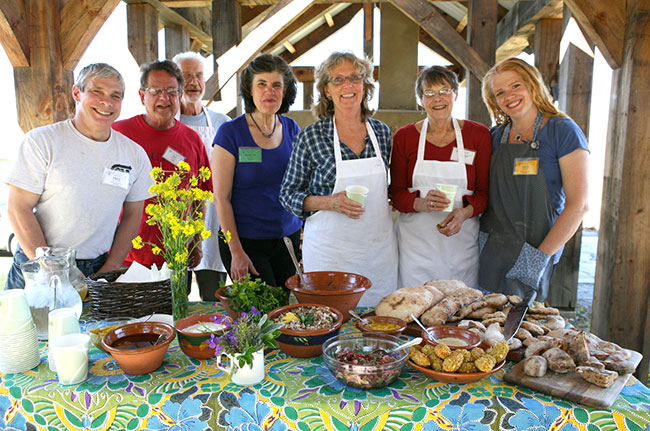 Nanette's flatbreads class poses under the timber frame pavilion for a photo with their delicious creations