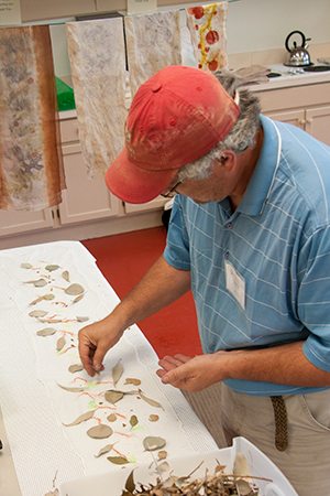 A student places leaves and bark on the fabric in preparation for the dyeing.