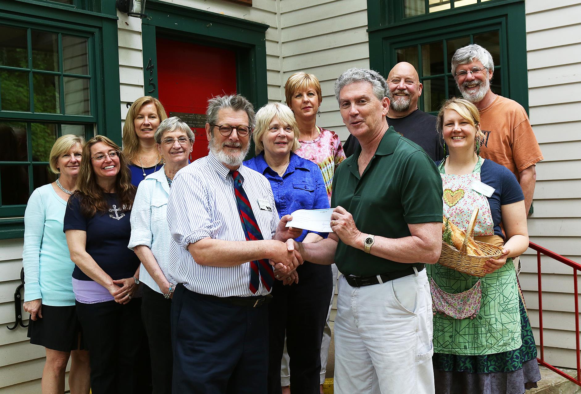 On May 10, 2016, the staff of John C. Campbell Folk School and Empty Bowls volunteers presented a check for $3,188 to Robert Merrill, President of Cherokee County Sharing Center. The Center provides food for over 400 families each month, 30% who are children. Presenting the check, Folk School Director Jan Davidson and Robert Merrill. Also pictured from left to right: Kate Delong, Ellen Sandor, Jennifer Slucher, Dianne Arnold, Marianne Hatchett, Colleen Plonsky, Mike Lalone, Cory Marie Podielski, and Harry Hearne. The Empty Bowls fundraiser for Cherokee and Clay County food banks has been organized by Resident Potter Mike Lalone and hosted by the John C. Campbell Folk School for the past 10 years.