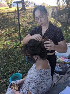 Mary Rubi, a fiber artist and costume designer in New York City, styles hair to match a photo of Louise Pittman