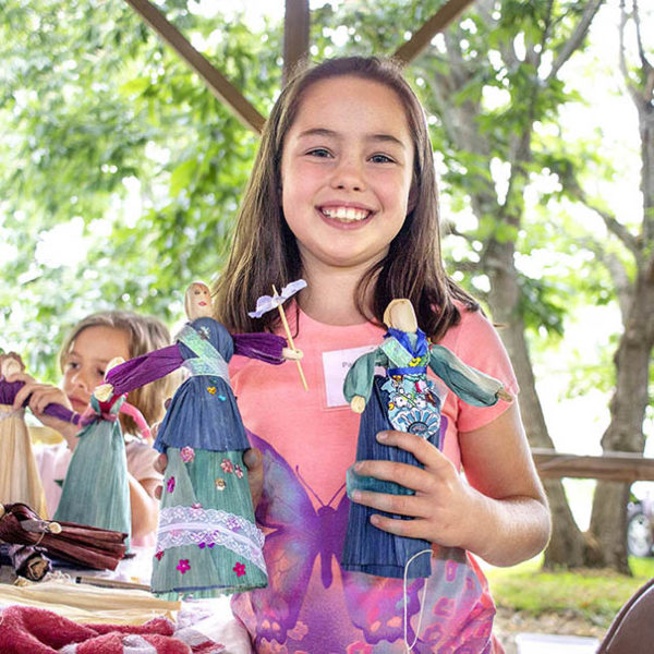 A student posing with their cornhusk doll creations