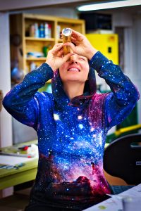 Looking inside a kaleidoscope A person wearing a galaxy-patterned hoodie is looking through a small cylindrical object.