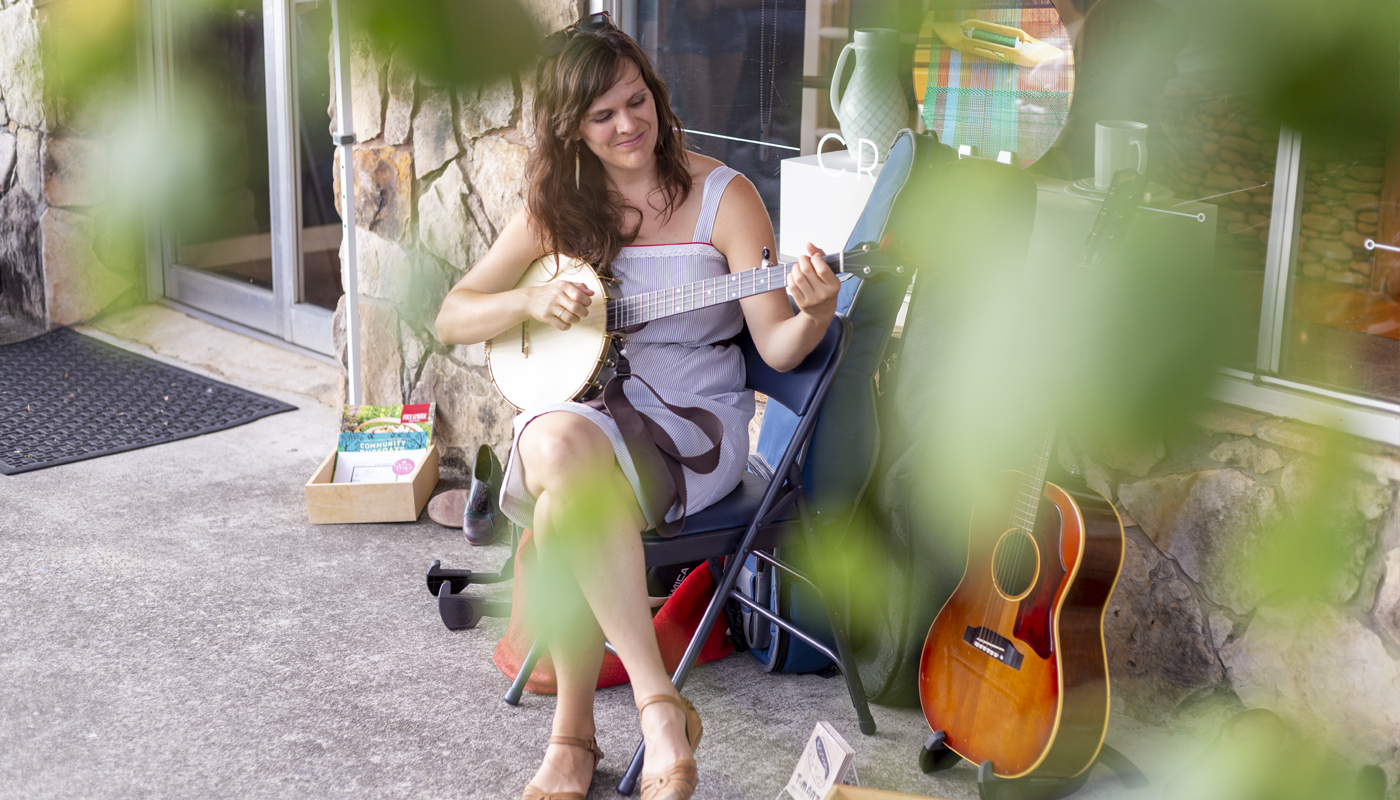 Becky Hill playing banjo outside of Olive's Porch, banner size