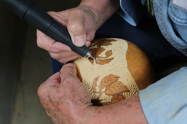 Person doing some woodburning techniques on a gourd.