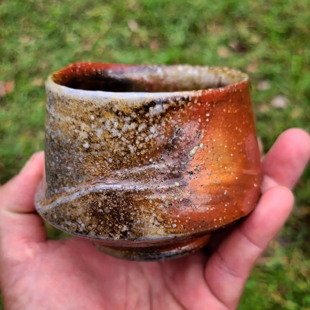 An orange and brown soda fired cup