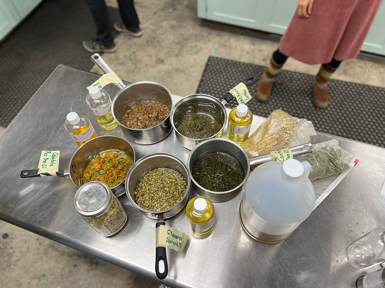 A table with five pans and many jars and bottles of essential oils and custom mixtures