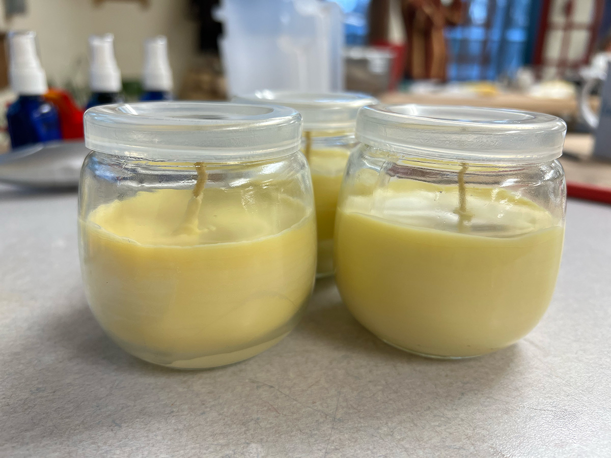 Three small glass jars with beeswax candles