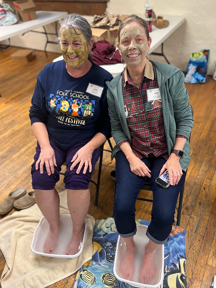 Two women sit next to each other, their faces covered in a liquid face mask made in Allison's class.