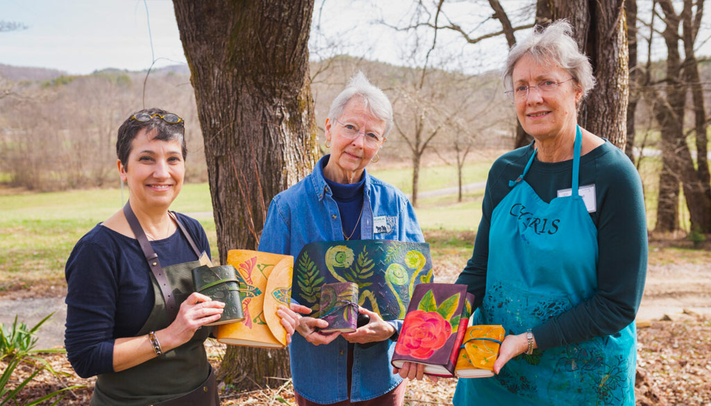 Three female students showing oof their recently book bindings.