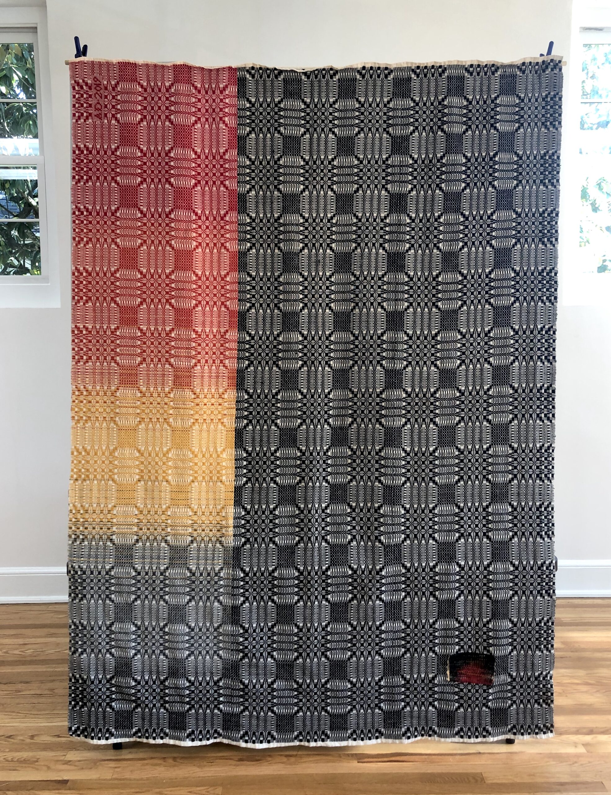 Allie Dudley - Keep Me Warm coverlet 1 coverlet with black and white pattern on right 2/3 and sections of red and white and yellow and white pattern on left