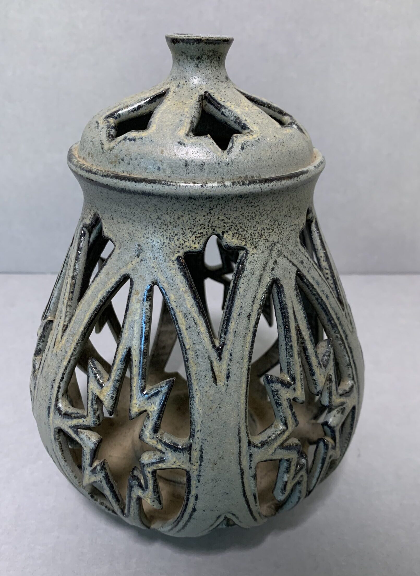 blue-gray ceramic candleholder with star-shaped cut-outs and lid
