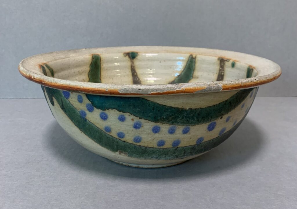 beige glazed bowl with wide rim and green and blue slip designs