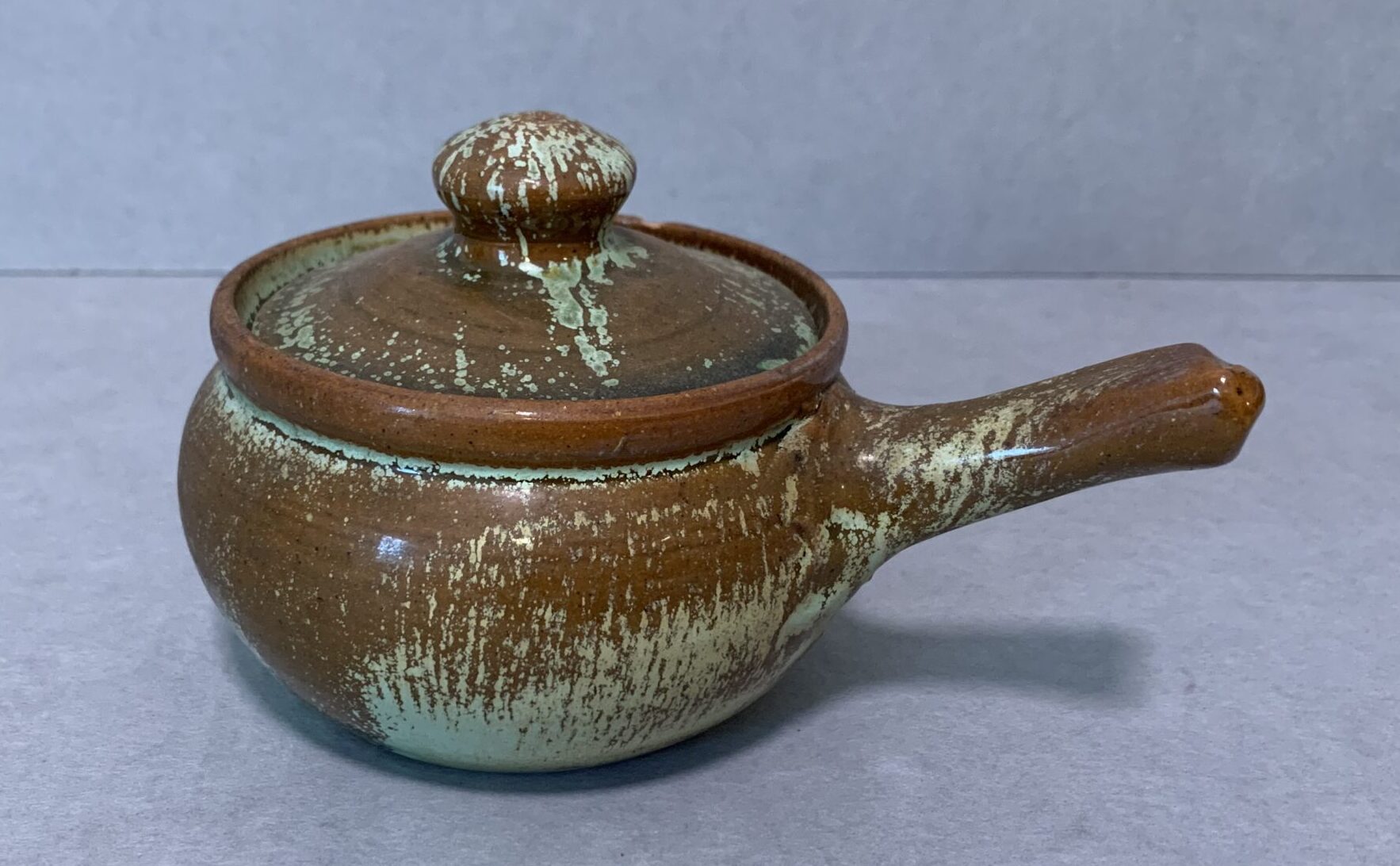 brown glazed ceramic ramekin and lid with light green marks
