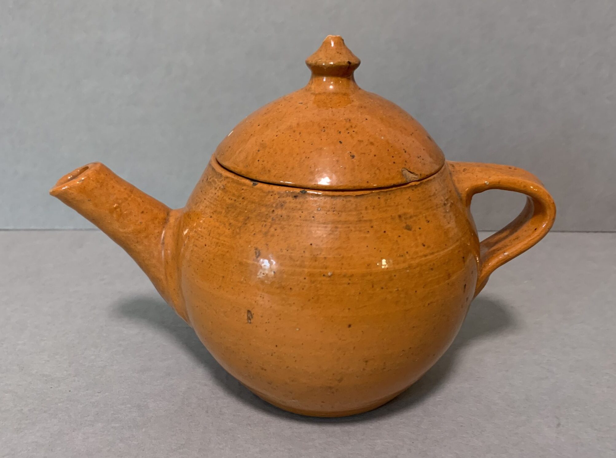 orange glazed ceramic teapot and lid