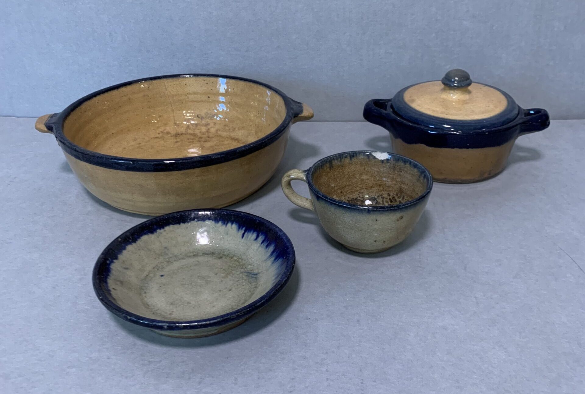 set of mismatched yellow or gray ceramic dishes with blue rims