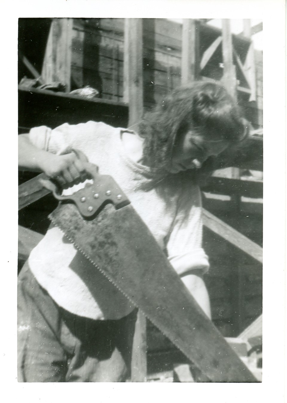 2025-45-014 black-and-white photo of a woman using a large handsaw