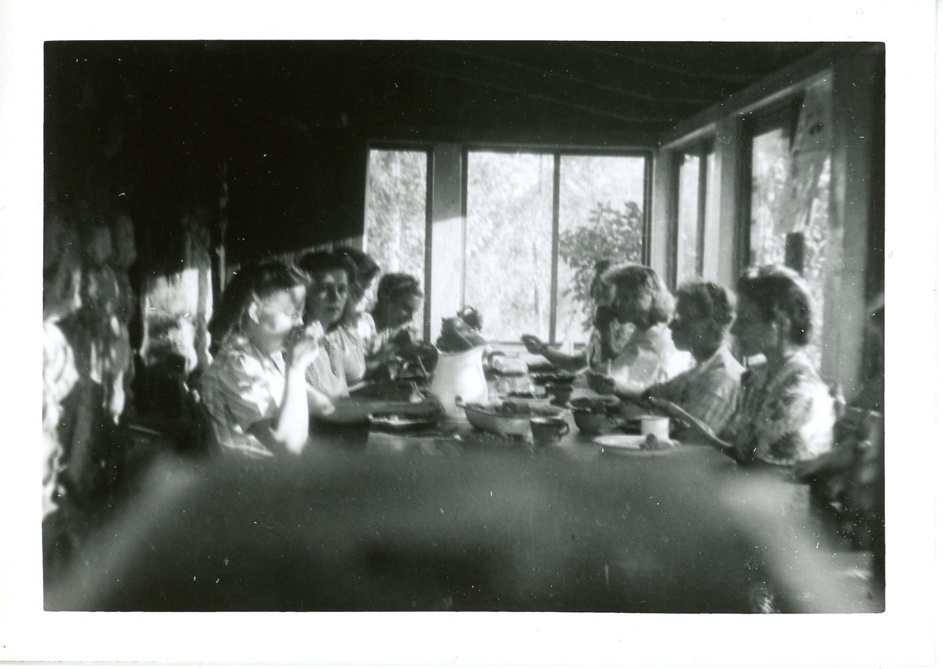 2025-45-032 black-and-white photo of eight women in 1940s dresses eating at a table