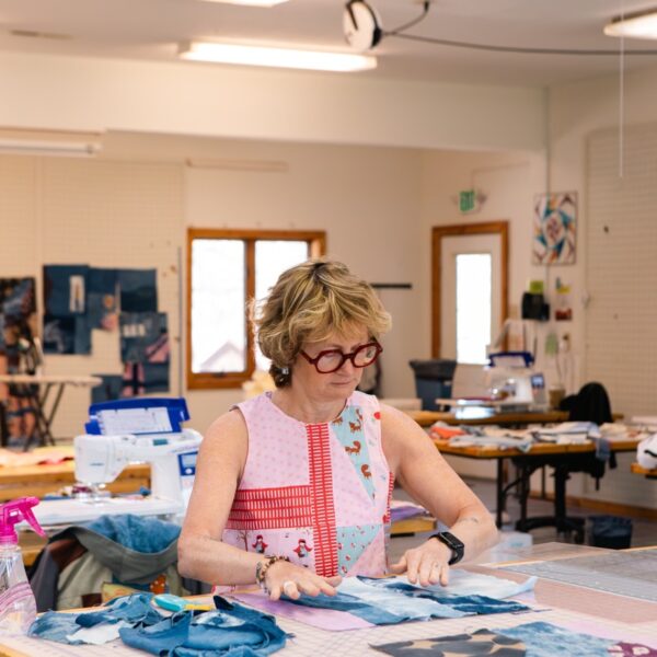 A person is working with textiles in a crafting room, possibly at a folk school.